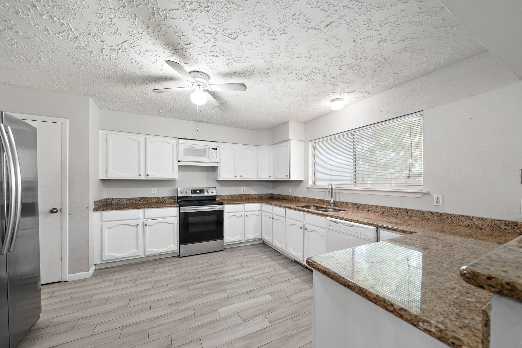 13923 Ludgate Pass Houston, TX 77034 - Photo 10 of 25 a large kitchen with cabinets wooden floor and stainless steel appliances