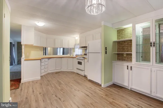 a kitchen with white cabinets and wooden floor