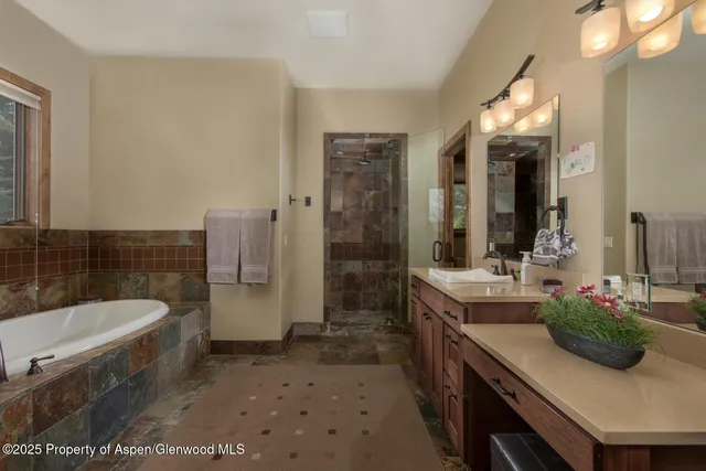 a bathroom with a tub a sink and a large mirror
