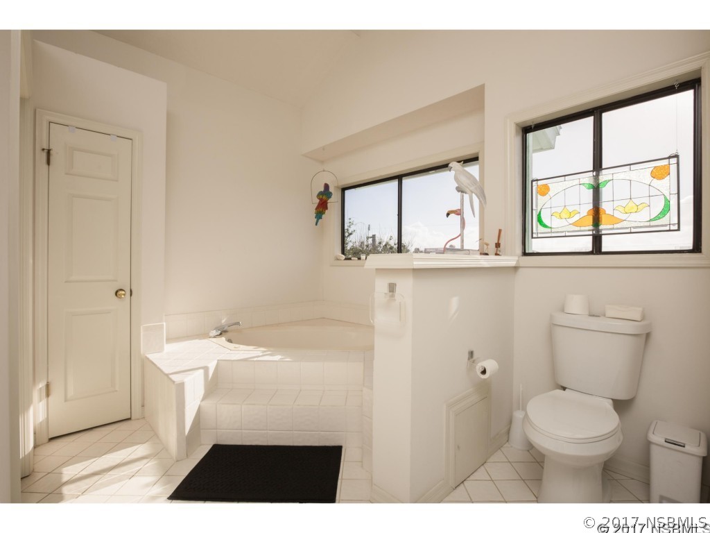 6455 Engram Road New Smyrna Beach, FL 32169 - Photo 23 of 33 a bathroom with a toilet a sink a vanity and mirror