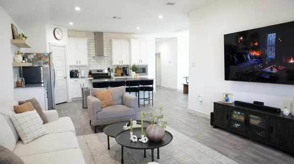 a living room with furniture a flat screen tv and kitchen view