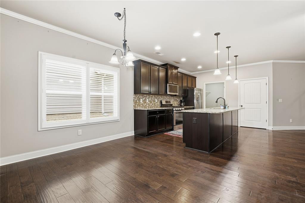 163 Hawthorne Ridge Circle Dallas, GA 30132 - Photo 17 of 50 a kitchen with stainless steel appliances kitchen island granite countertop a stove a refrigerator a sink a oven and a wooden floors