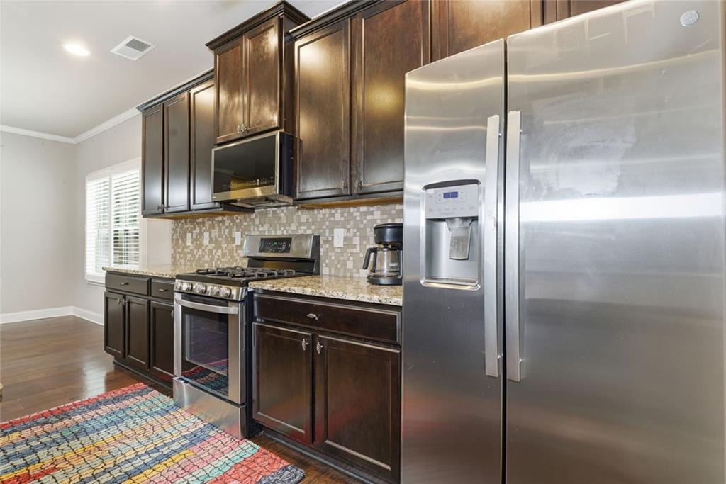 163 Hawthorne Ridge Circle Dallas, GA 30132 - Photo 22 of 50 a kitchen with stainless steel appliances granite countertop a refrigerator a stove and a sink with wooden floor