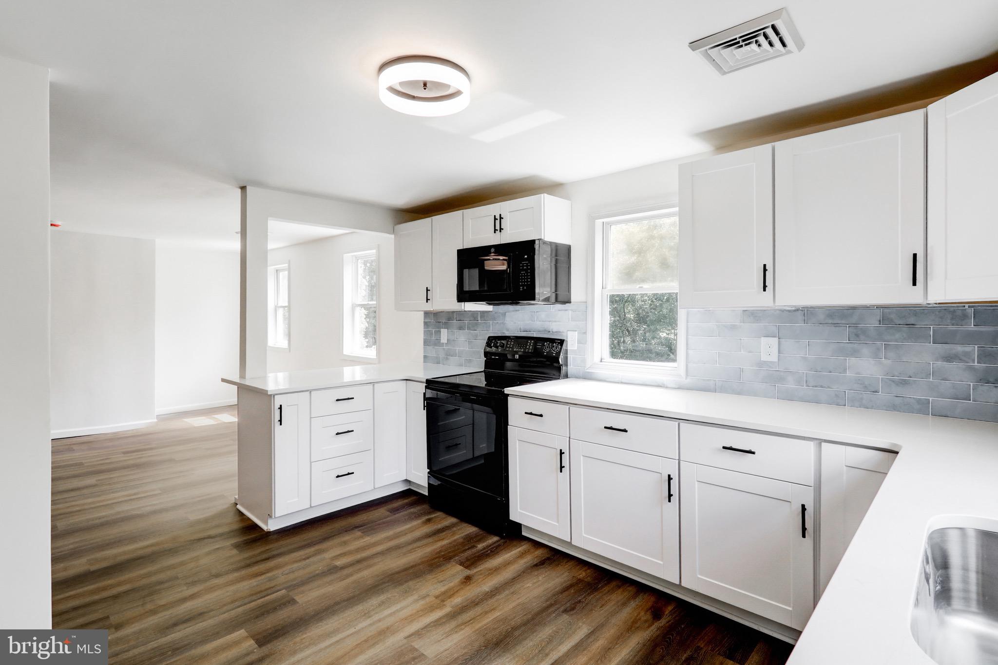 2145 Dunks Ferry Road Bensalem, PA 19020 - Photo 10 of 37 a kitchen with white cabinets and black appliances