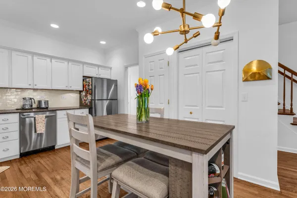 a kitchen with stainless steel appliances granite countertop a table chairs in it and wooden floors