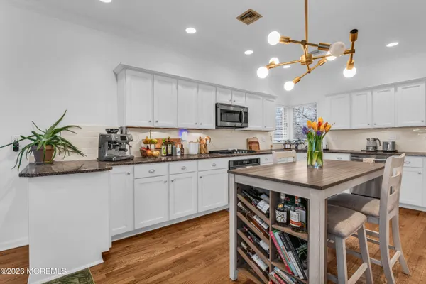 a kitchen with stainless steel appliances granite countertop a sink a stove and a wooden floors