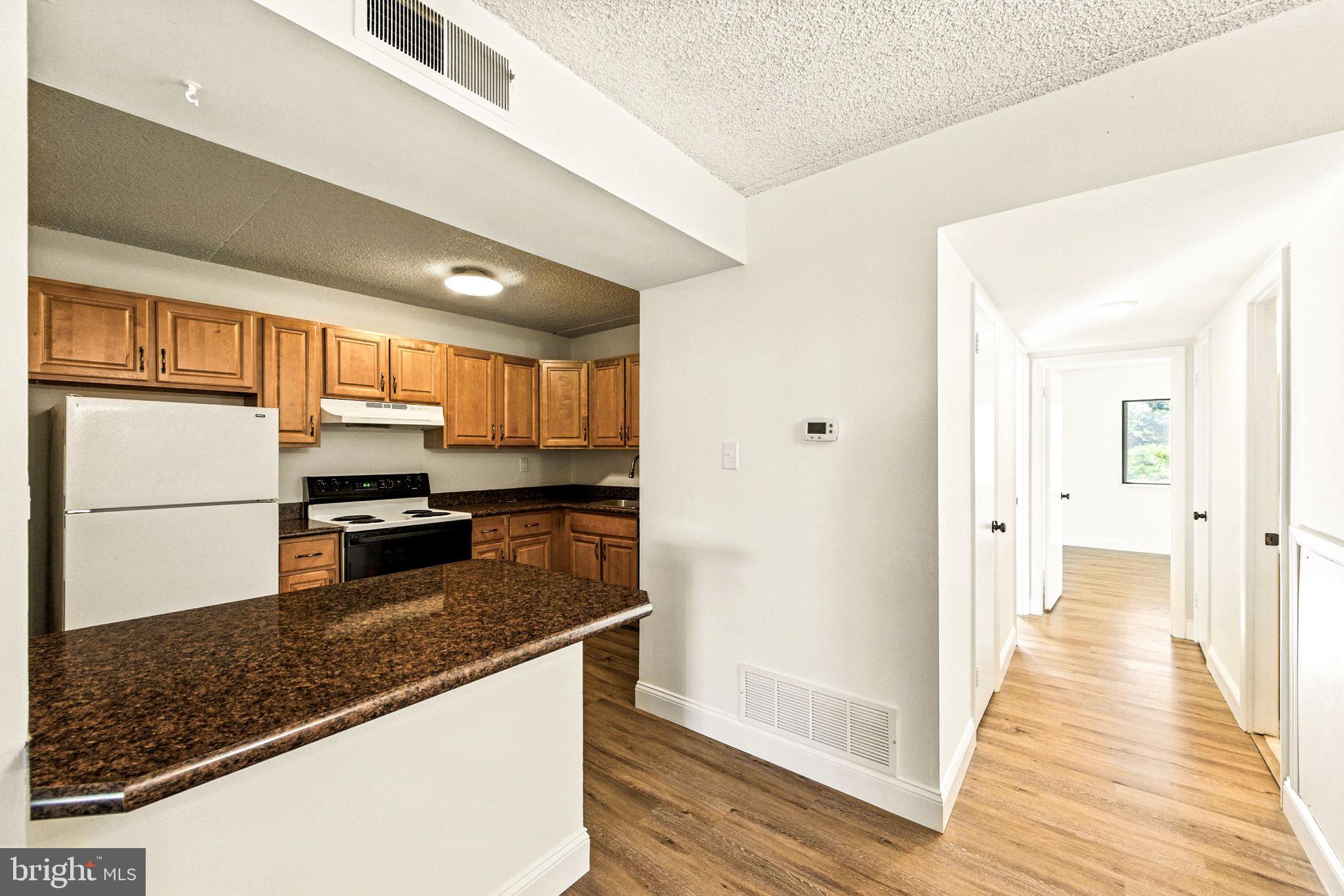 338 Saybrook Lane Wallingford, PA 19086 - Photo 13 of 30 a kitchen with stainless steel appliances granite countertop a refrigerator a stove and a sink with wooden floors