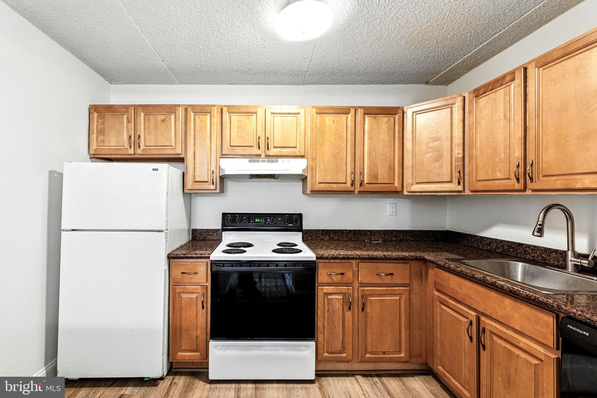 338 Saybrook Lane Wallingford, PA 19086 - Photo 14 of 30 a kitchen with stainless steel appliances granite countertop wooden cabinets a stove a sink and a refrigerator