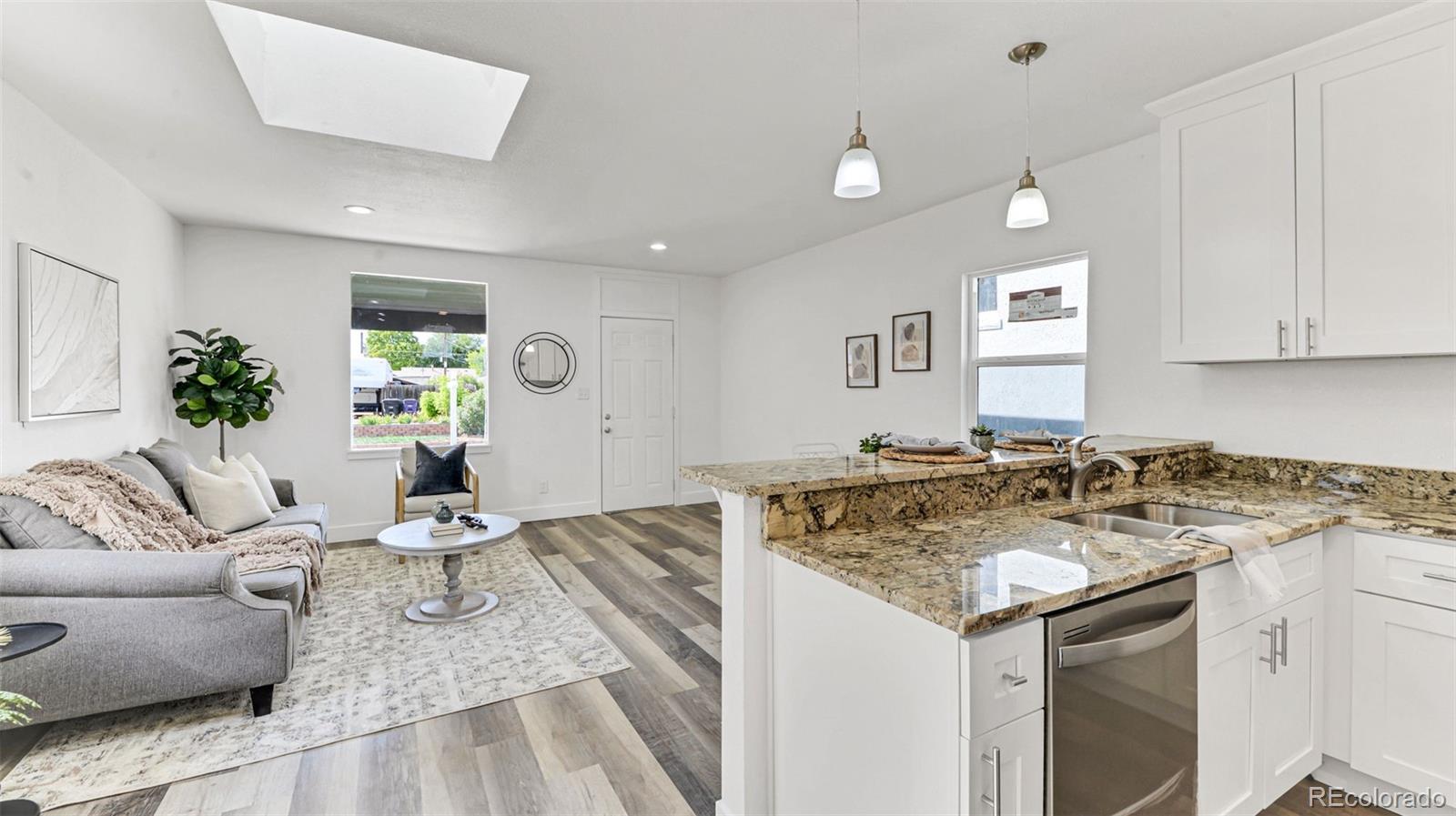 660 Meade Street Denver, CO 80204 - Photo 16 of 25 a view of a kitchen with kitchen island a stove a sink and a living room with a couch