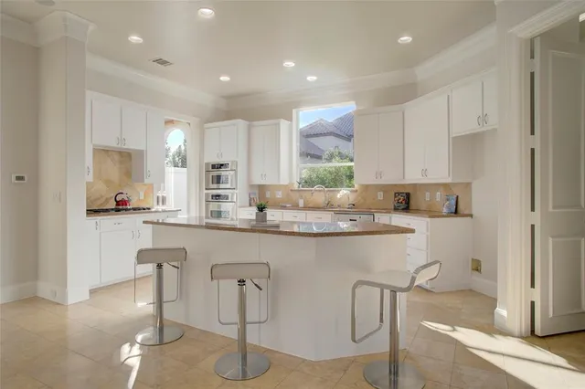 a kitchen with stainless steel appliances granite countertop a table and chairs in it