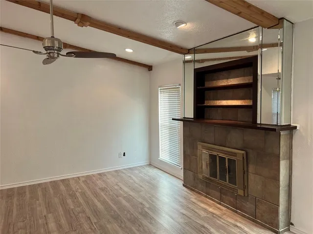 a view of an empty room with a fireplace and a window