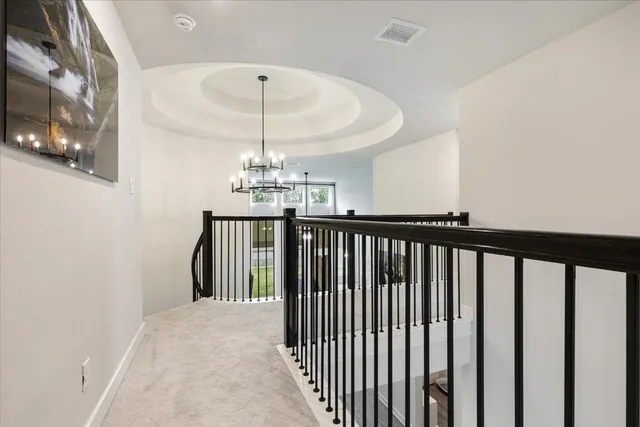 a view of a hallway with wooden floor and chandelier