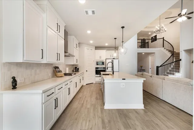 a large white kitchen with stainless steel appliances sink a microwave and cabinets