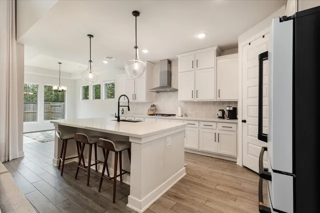 a kitchen with stainless steel appliances granite countertop a sink a stove a refrigerator and island with wooden floor