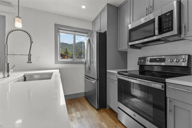 a kitchen with stainless steel appliances a stove microwave and sink
