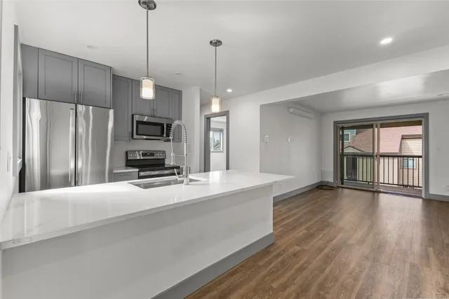 a large kitchen with kitchen island a large counter space a refrigerator and a view of living room