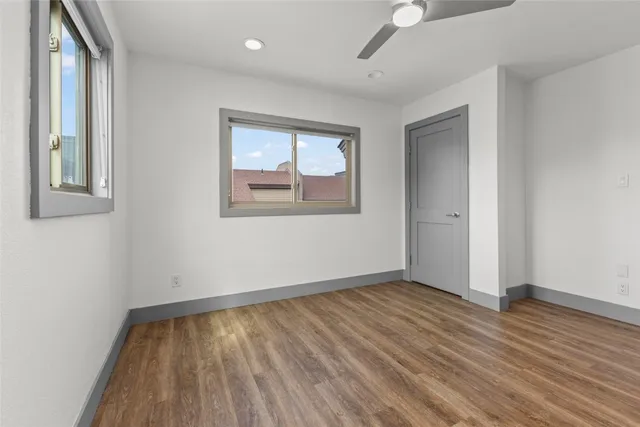 an empty room with wooden floor and windows