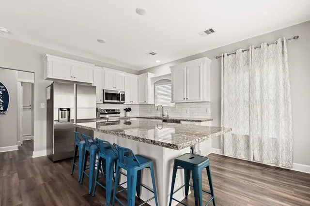 a kitchen with stainless steel appliances granite countertop a stove top oven a refrigerator a sink and dishwasher with wooden floor