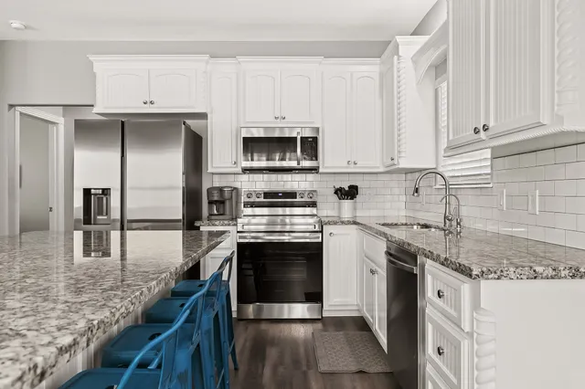 a kitchen with stainless steel appliances granite countertop a stove a sink and a refrigerator