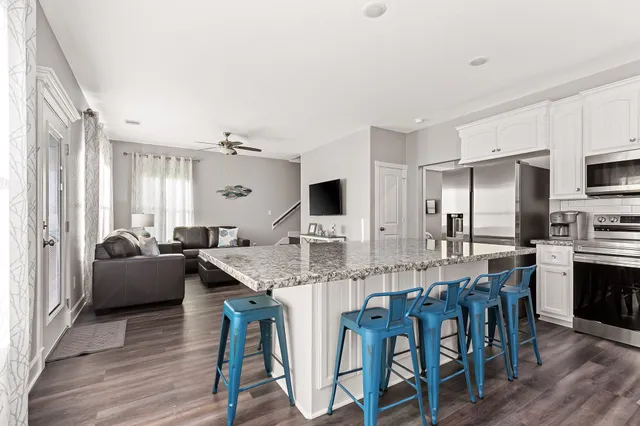 a kitchen with stainless steel appliances granite countertop a dining table chairs and granite counter tops