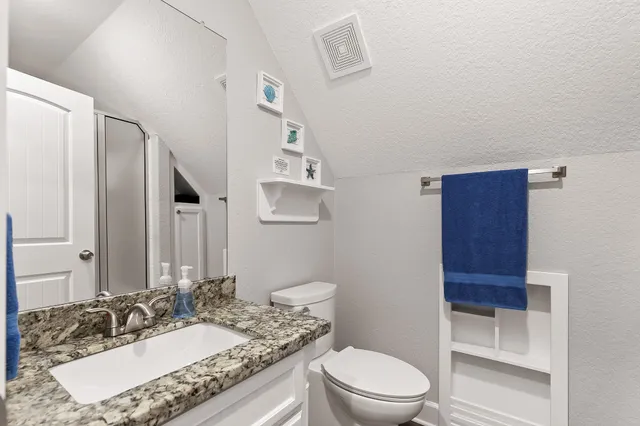 a bathroom with a granite countertop sink toilet a mirror and shower
