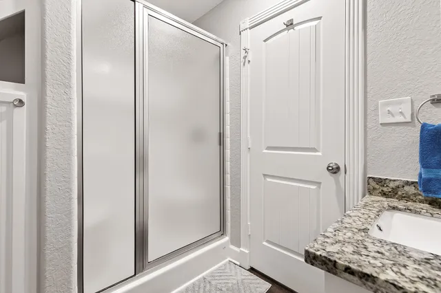 a bathroom with a granite countertop sink and shower