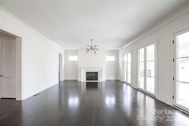 an empty room with wooden floor fireplace and windows