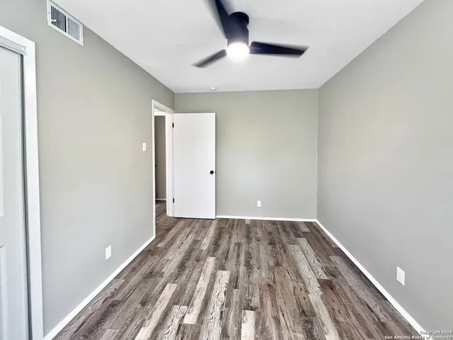 a view of a room with wooden floor and a ceiling fan