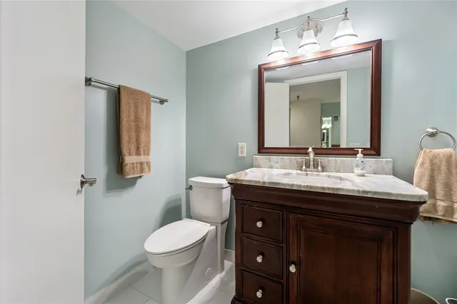 a bathroom with a granite countertop sink toilet and mirror