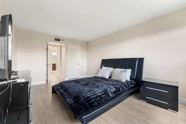 a large bed sitting in a bedroom next to a window with wooden floor
