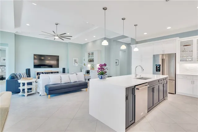 a large white kitchen with a large island oven a stove and a chandelier