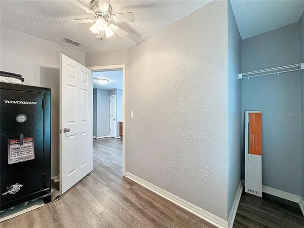 an empty room with wooden floor fan and windows