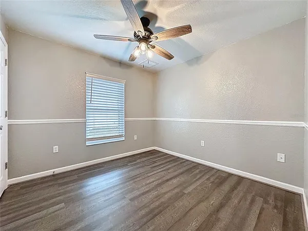 a view of empty room with wooden floor and fan