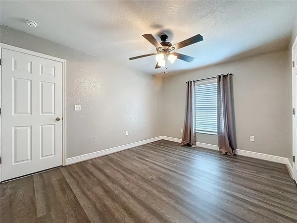 a view of an empty room with window and wooden floor