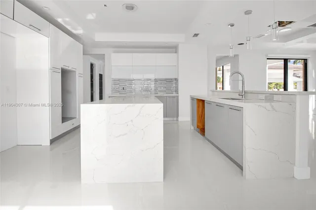 a large white kitchen with cabinets a sink and a refrigerator