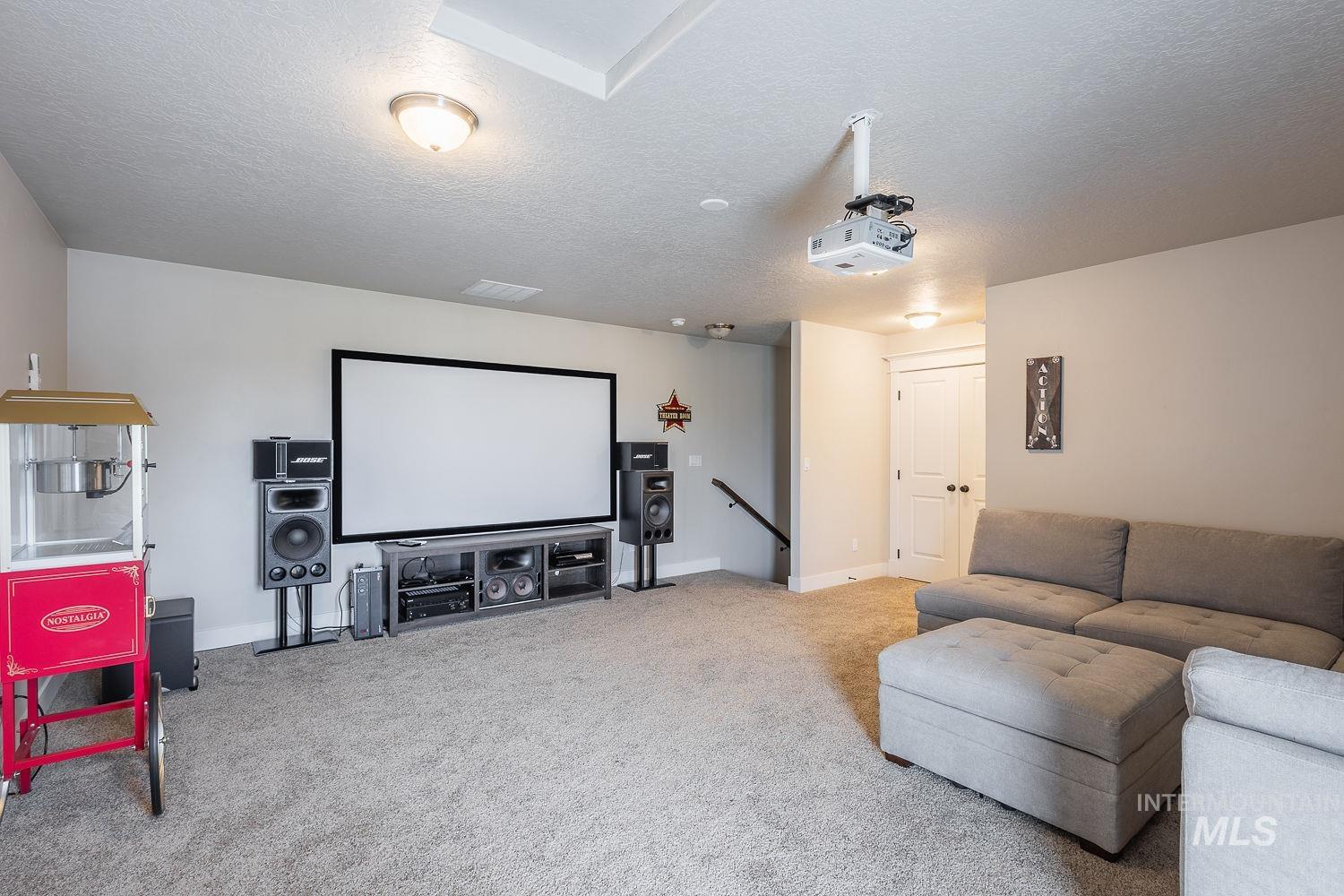 8077 Star Pass Ridge Road Nampa, ID 83686 - Photo 34 of 37 Dedicated entertainment room featuring a large projection screen, ceiling-mounted projector, and carpeted flooring