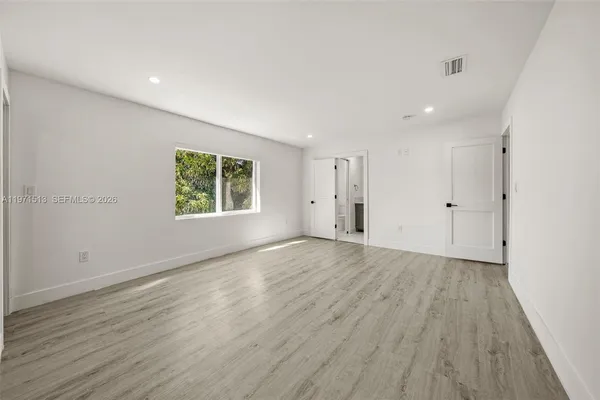 an empty room with wooden floor and windows