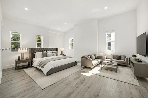 a spacious bedroom with a bed a couch and a flat tv screen on the dresser