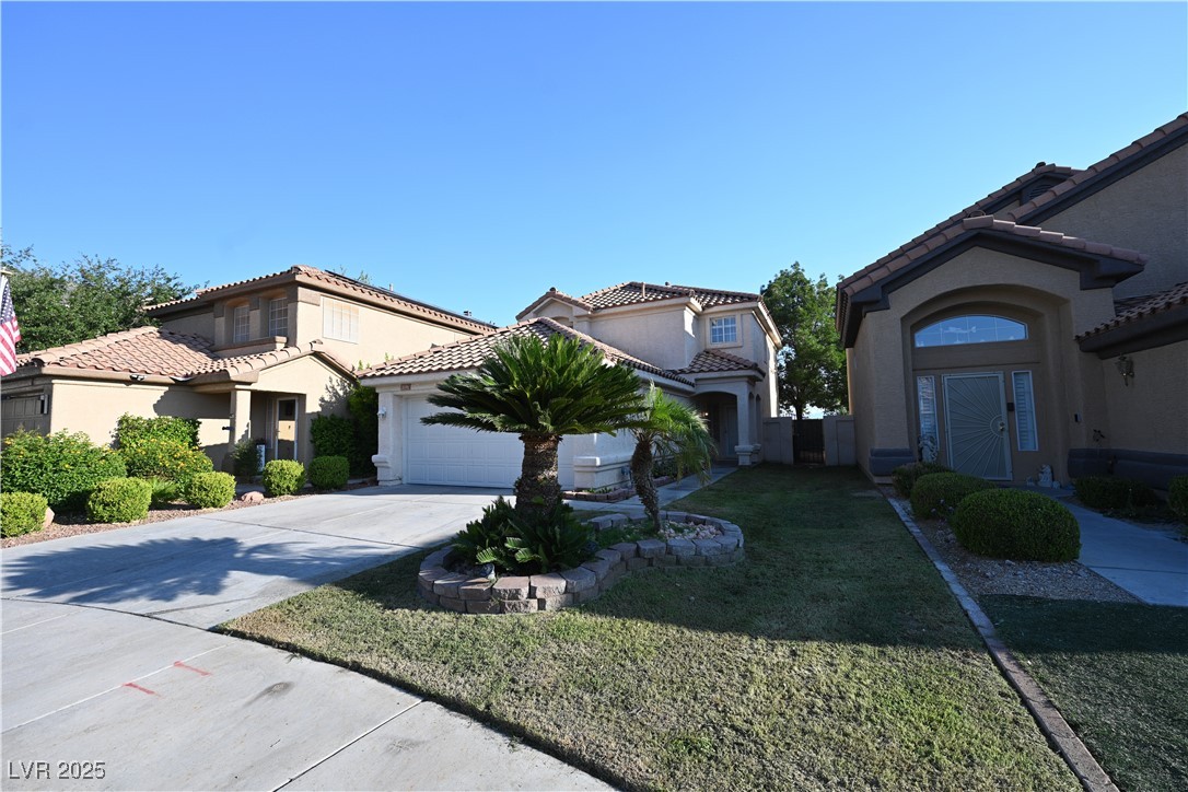 Mediterranean / spanish home with an attached garage, stucco siding, driveway, a front yard, and a tile roof