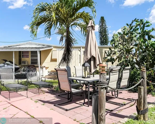 a view of a patio with table and chairs potted plants and palm tree