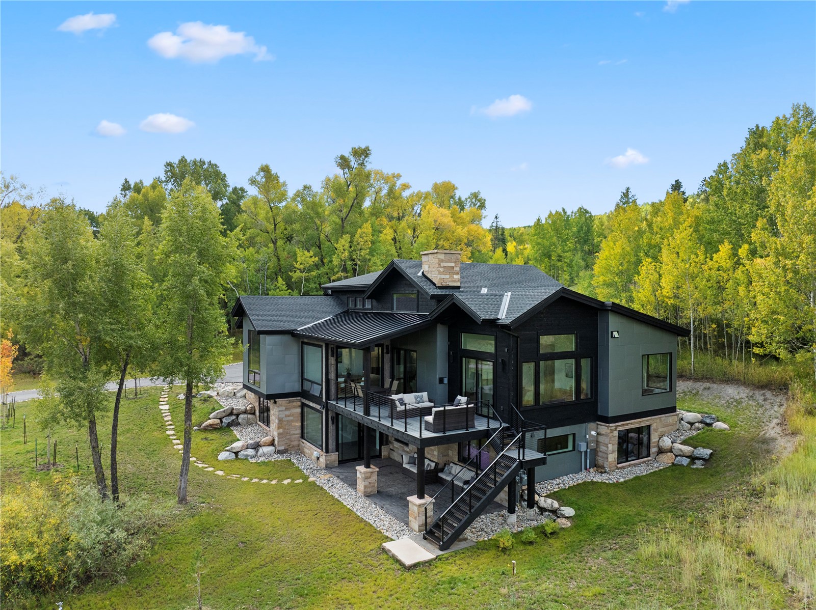 149 Game Trail Road Silverthorne, CO 80498 - Photo 46 of 49 Back of house featuring a sunroom, a chimney, stairway, a patio area, and stone siding