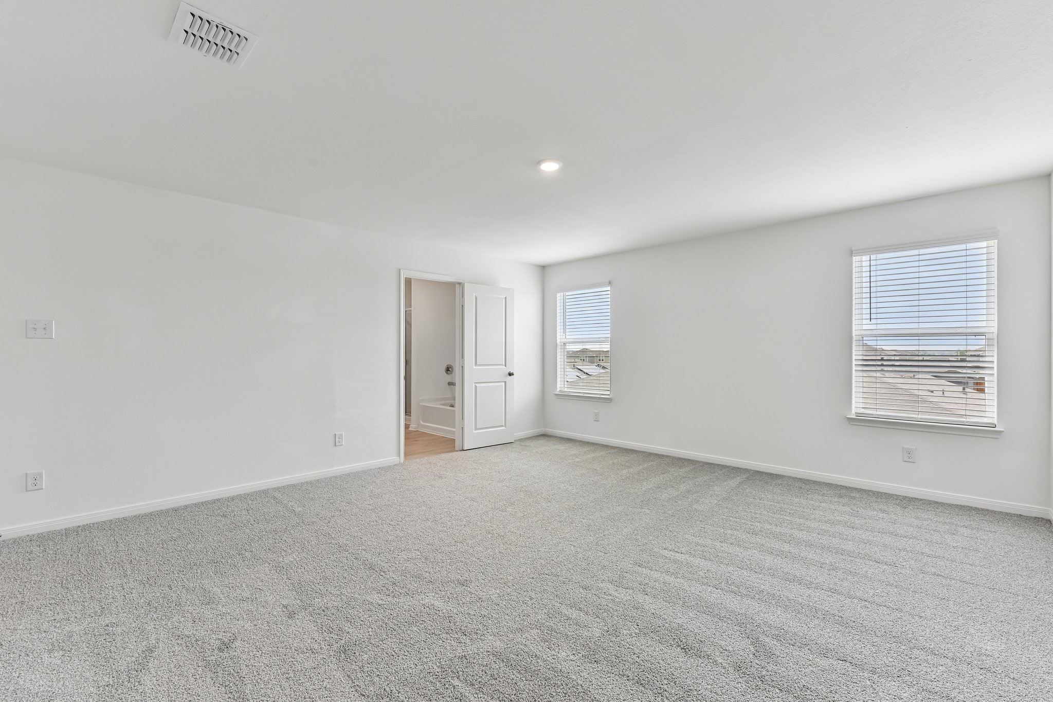 346 Low Pasture Trail Maxwell, TX 78656 - Photo 20 of 29 Spacious room featuring light gray carpeting, neutral wall paint, two windows with blinds, a recessed ceiling light, and an open doorway revealing a bathtub