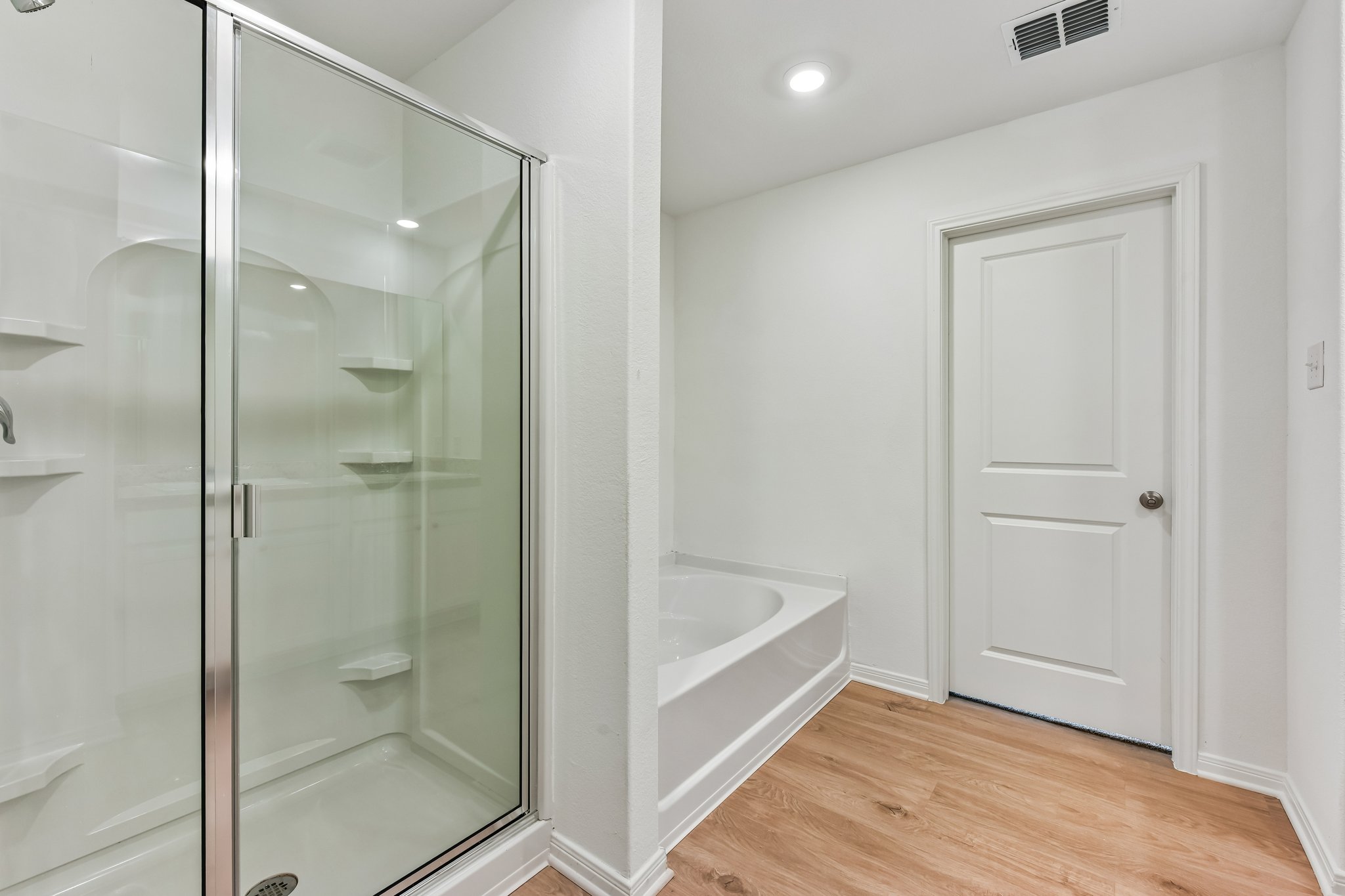 346 Low Pasture Trail Maxwell, TX 78656 - Photo 22 of 29 Full bathroom featuring a glass-enclosed shower with integrated shelving, a built-in bathtub, wood-finish flooring, a white paneled door, and recessed lighting