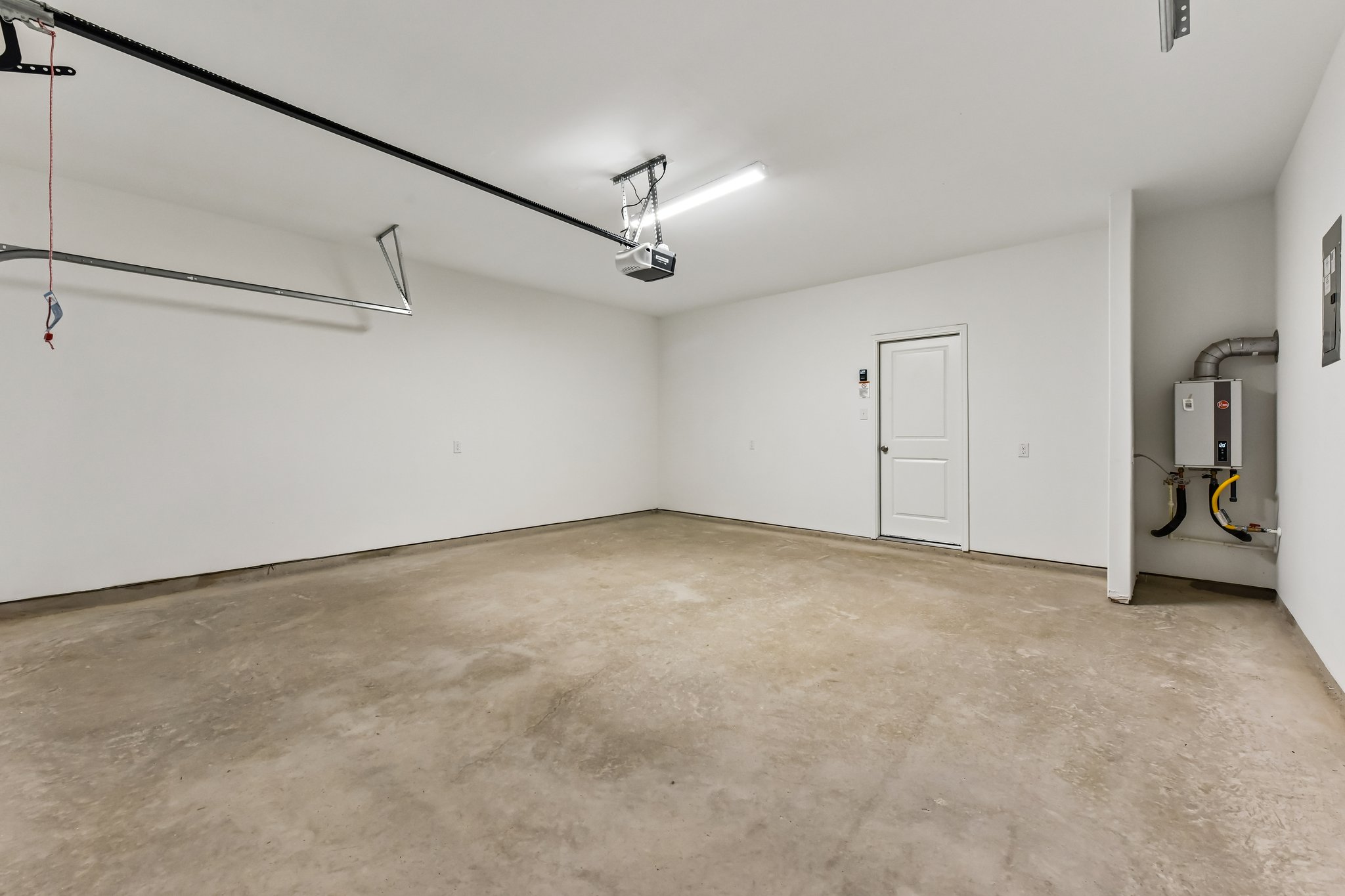 346 Low Pasture Trail Maxwell, TX 78656 - Photo 26 of 29 Spacious garage with a concrete floor, painted white walls, overhead lighting, and an automatic garage door opener