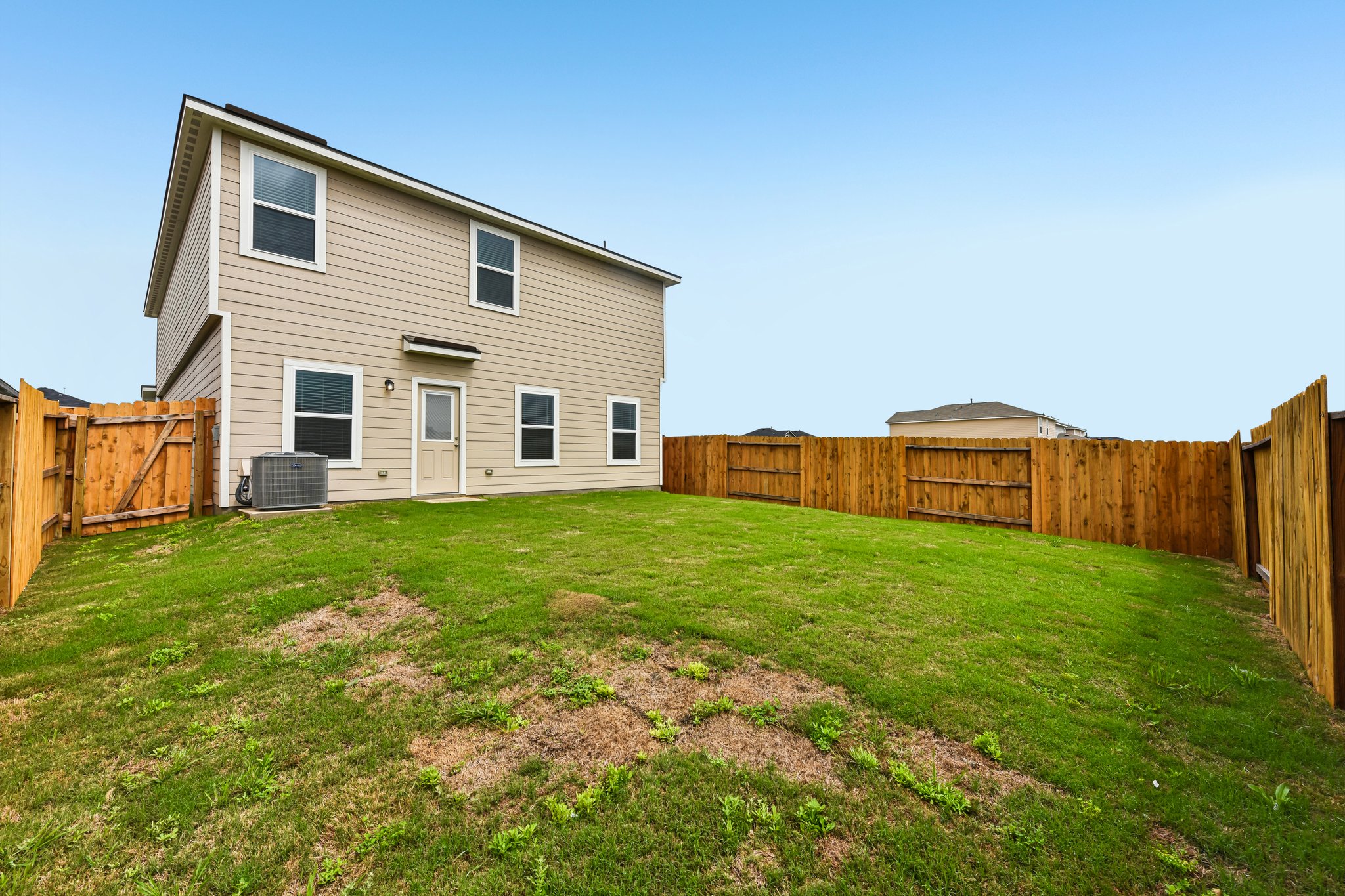346 Low Pasture Trail Maxwell, TX 78656 - Photo 29 of 29 Spacious backyard featuring a full wood privacy fence, a manicured lawn, and a light-colored stucco exterior with multiple windows