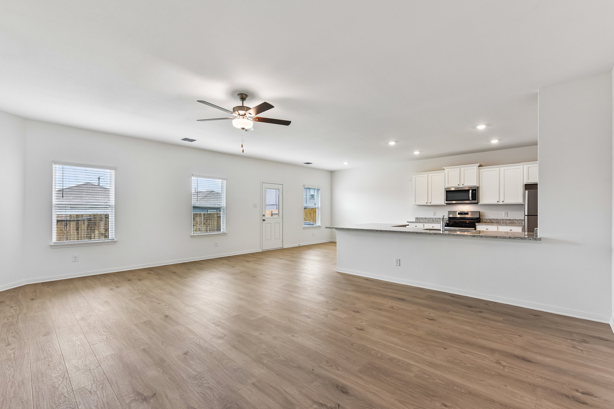 346 Low Pasture Trail Maxwell, TX 78656 - Photo 3 of 29 Open-concept living area featuring wood-finish flooring, a ceiling fan with integrated lighting, recessed lighting, white cabinetry, and stainless steel appliances