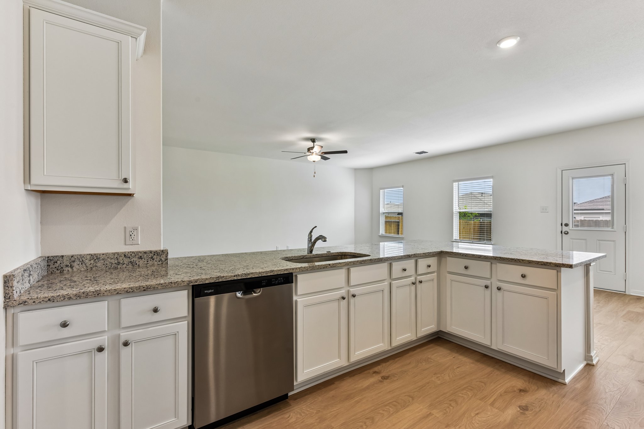 346 Low Pasture Trail Maxwell, TX 78656 - Photo 7 of 29 Kitchen featuring a large peninsula with a stainless steel sink, granite countertops, white cabinetry, and wood-finish flooring