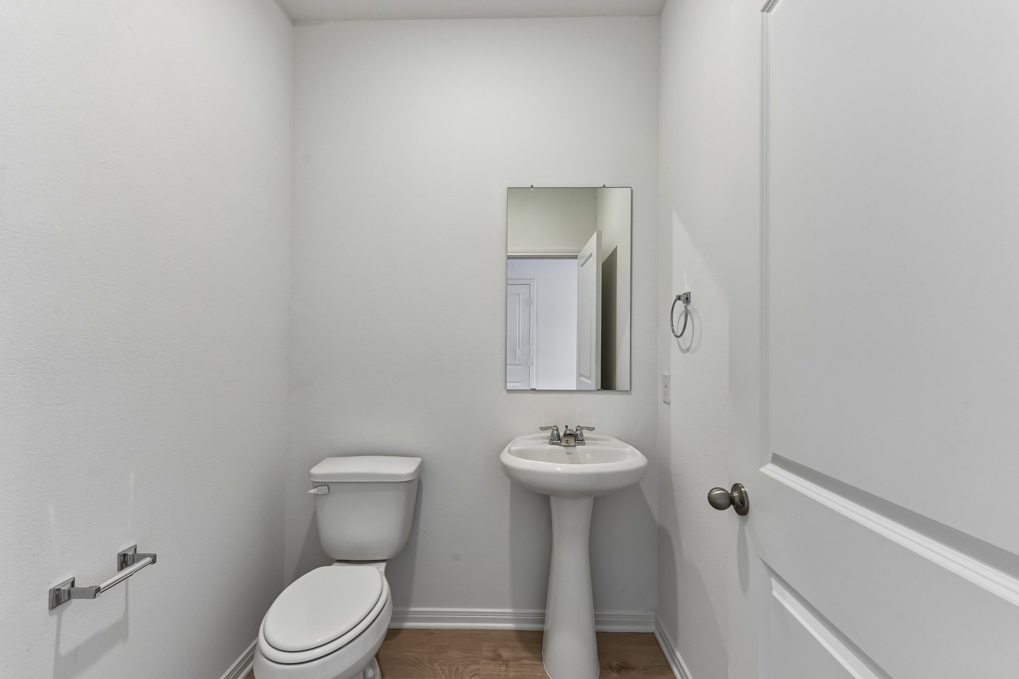 346 Low Pasture Trail Maxwell, TX 78656 - Photo 8 of 29 Pedestal sink with chrome faucet, a rectangular wall-mounted mirror, and wood-finish flooring