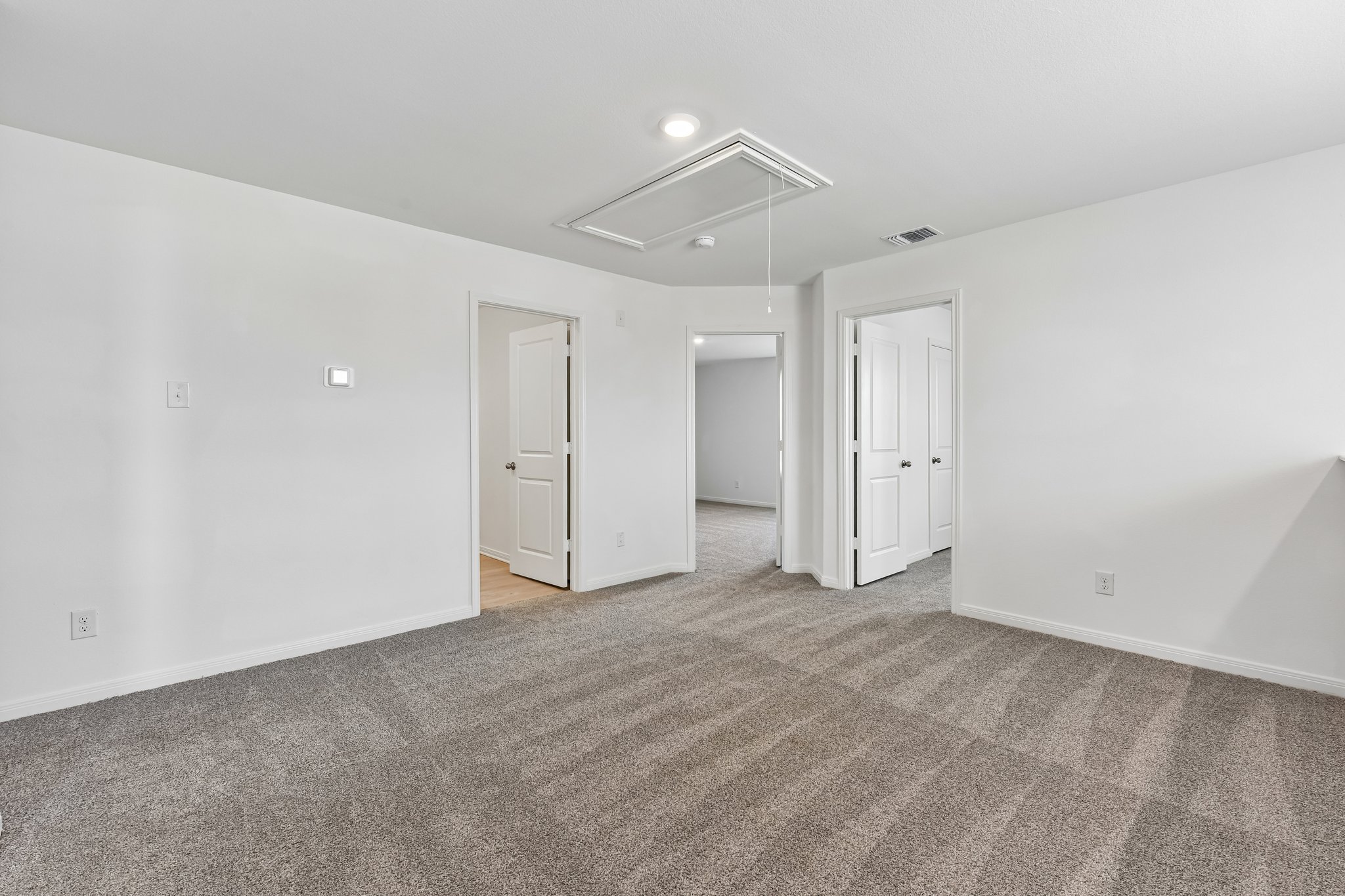 346 Low Pasture Trail Maxwell, TX 78656 - Photo 9 of 29 Spacious carpeted room featuring multiple doorways, white painted walls, and a ceiling-mounted access panel