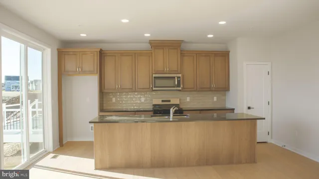 a view of a kitchen with kitchen island a sink wooden floor and a counter top space
